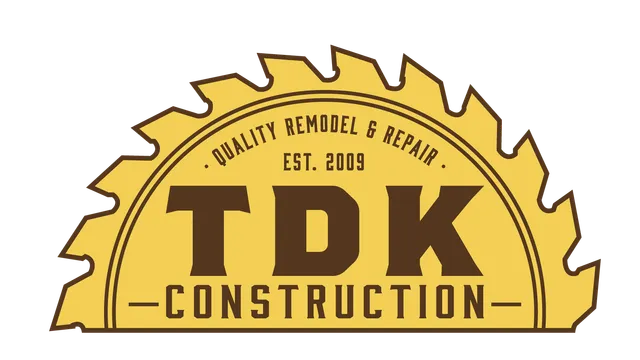 A yellow, semi-circular saw blade logo for TDK Construction, featuring the text