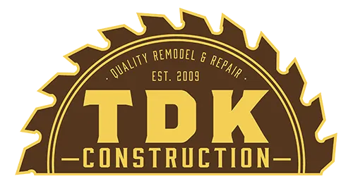 Logo for TDK Construction, featuring text framed by a saw blade silhouette in brown and gold colors.